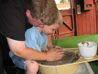 [Photo: Faythe getting pottery lessons]